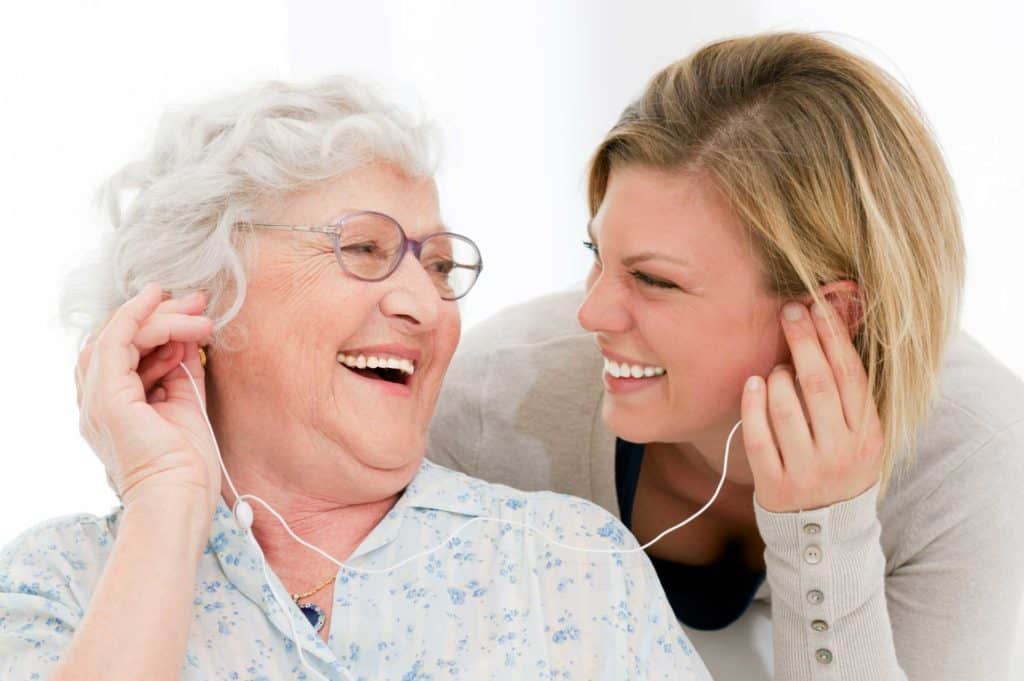 pictured elderly woman and caregiver listening to music at memory care community The Legacy at Highwoods Preserve